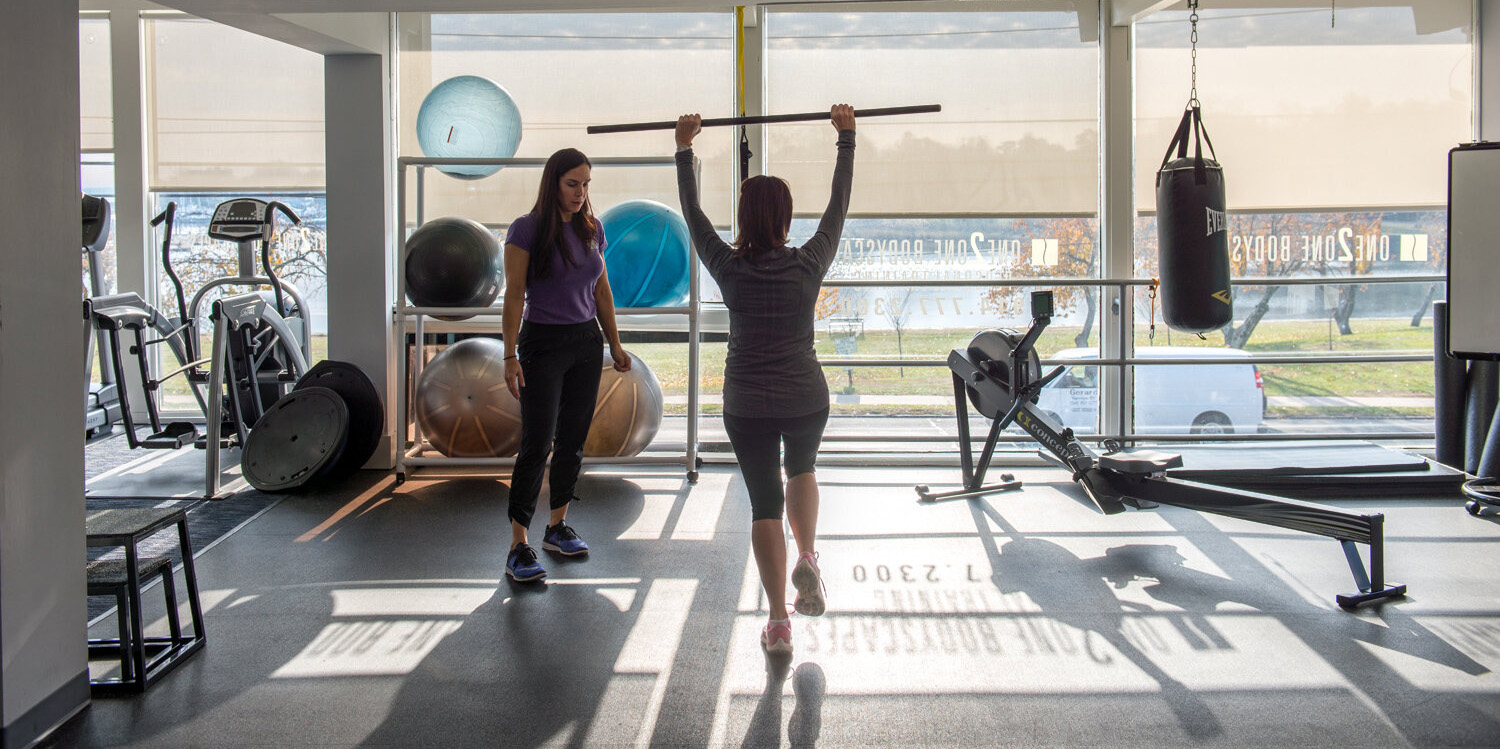 Certified personal trainer demonstrating proper exercise form with client